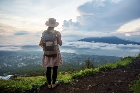 Woman enjoying sunrise from a top of mountain Batur, Bali, Indonesia.の写真素材