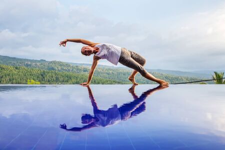 Caucasian woman practicing yoga by the poolの写真素材