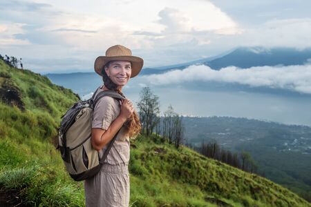 Woman enjoying sunrise from a top of mountain Batur, Bali, Indonesia.の写真素材