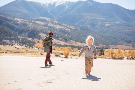 A man with his son are hiking in desertの写真素材