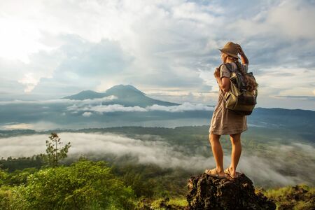 Woman enjoying sunrise from a top of mountain Batur, Bali, Indonesia.の写真素材