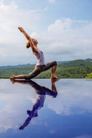 Caucasian woman practicing yoga by the poolの写真素材