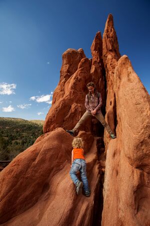 Mom and her son climbing rocksの写真素材
