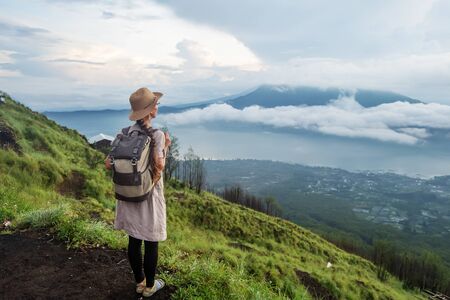 Woman enjoying sunrise from a top of mountain Batur, Bali, Indonesia.の写真素材