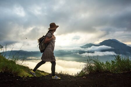 Woman enjoying sunrise from a top of mountain Batur, Bali, Indonesia.の写真素材