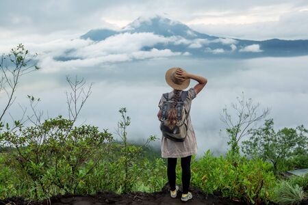 Woman enjoying sunrise from a top of mountain Batur, Bali, Indonesia.の写真素材