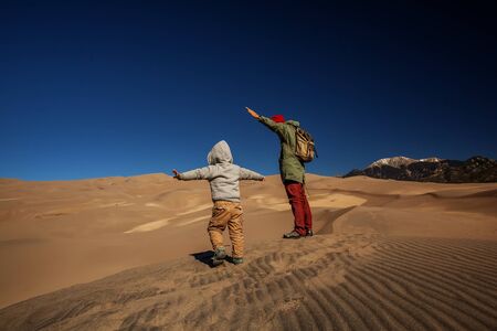 A man with his son are hiking in desertの写真素材