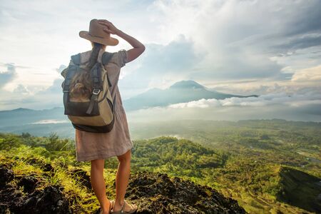 Woman enjoying sunrise from a top of mountain Batur, Bali, Indonesia.の写真素材