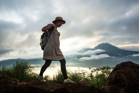 Woman enjoying sunrise from a top of mountain Batur, Bali, Indonesia.の写真素材