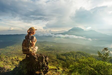 Woman enjoying sunrise from a top of mountain Batur, Bali, Indonesia.の写真素材