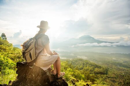 Woman enjoying sunrise from a top of mountain Batur, Bali, Indonesia.の写真素材