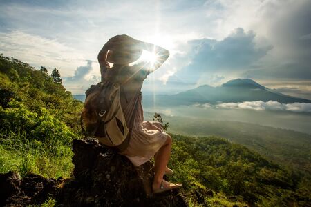 Woman enjoying sunrise from a top of mountain Batur, Bali, Indonesia.の写真素材