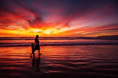 mother and son having fun at sunset on the beachの写真素材