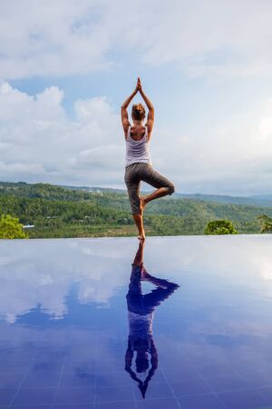 Caucasian woman practicing yoga by the poolの写真素材