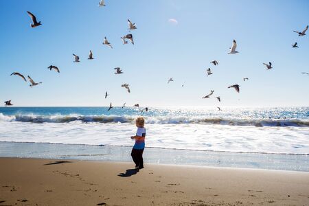 Happy and free boy on the beach with seagullsの写真素材