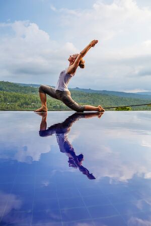 Caucasian woman practicing yoga by the poolの写真素材