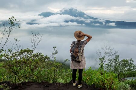 Woman enjoying sunrise from a top of mountain Batur, Bali, Indonesia.の写真素材