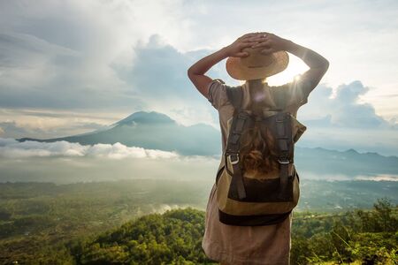 Woman enjoying sunrise from a top of mountain Batur, Bali, Indonesia.の写真素材