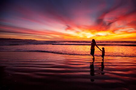 mother and son having fun at sunset on the beachの写真素材