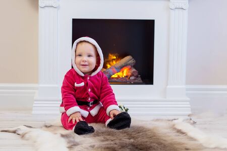 Small boy in Santa suit plays near new-year treeの写真素材
