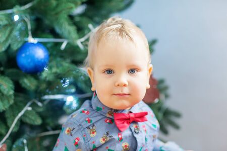Small boy in Santa suit plays near new-year treeの写真素材