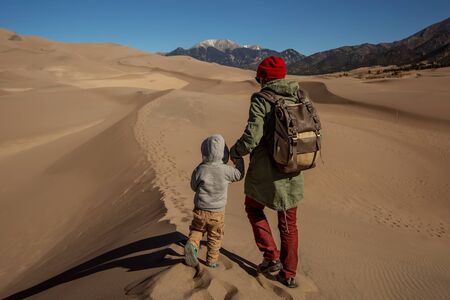 A man with his son are hiking in desertの写真素材