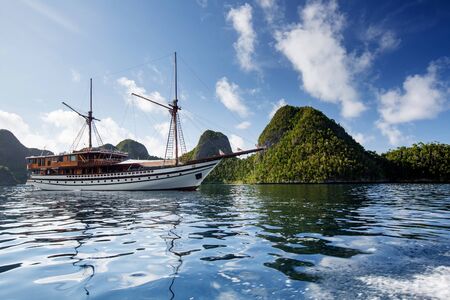 Sail boat between islands of remote archipelago Pulau Wayag, Raja Ampat, Indonesiaの写真素材