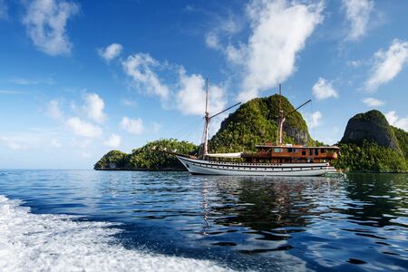 Sail boat between islands of remote archipelago Pulau Wayag, Raja Ampat, Indonesiaの写真素材