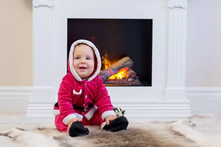 Small boy in Santa suit plays near new-year treeの写真素材