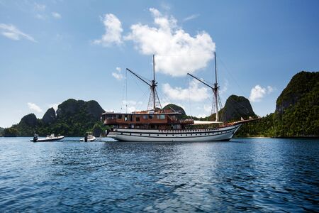 Sail boat between islands of remote archipelago Pulau Wayag, Raja Ampat, Indonesiaの写真素材