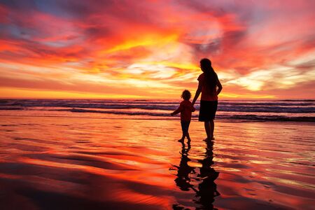 mother and son having fun at sunset on the beachの写真素材