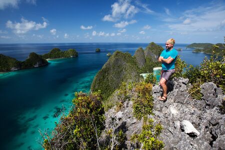 Tourists are on the top of the cliff of remote archipelago Pulau Wayag, Raja Ampat, Indonesiaの写真素材