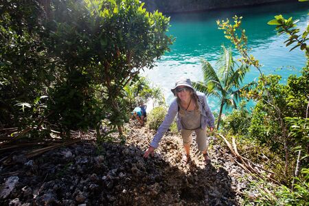 Tourists climb to the top of the cliff of remote archipelago Pulau Wayag, Raja Ampat, Indonesiaの写真素材