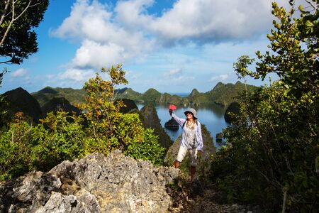 Tourists are on the top of the cliff of remote archipelago Pulau Wayag, Raja Ampat, Indonesiaの写真素材