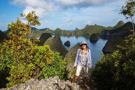 Tourists are on the top of the cliff of remote archipelago Pulau Wayag, Raja Ampat, Indonesiaの写真素材