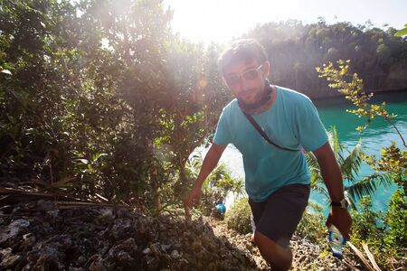 Tourists climb to the top of the cliff of remote archipelago Pulau Wayag, Raja Ampat, Indonesiaの写真素材