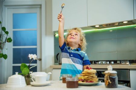 Little curly boy eating sweet pancakesの写真素材