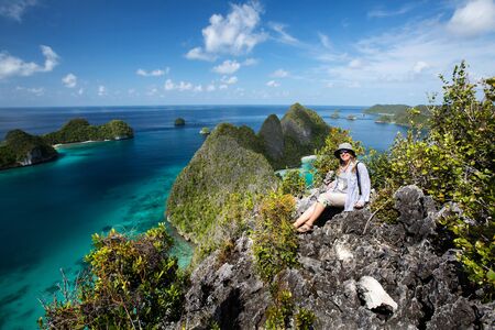 Tourists are on the top of the cliff of remote archipelago Pulau Wayag, Raja Ampat, Indonesiaの写真素材