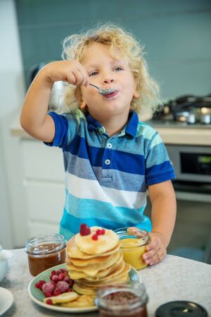 Little curly boy eating sweet pancakesの写真素材