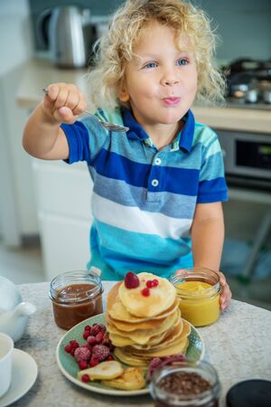 Little curly boy eating sweet pancakesの写真素材