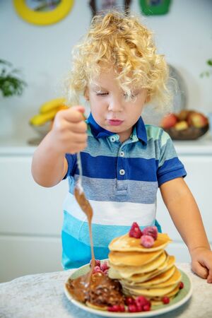 Little curly boy eating sweet pancakesの写真素材