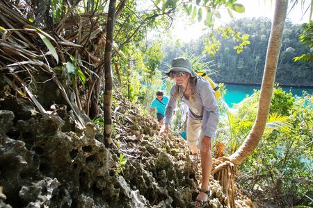 Tourists climb to the top of the cliff of remote archipelago Pulau Wayag, Raja Ampat, Indonesiaの写真素材