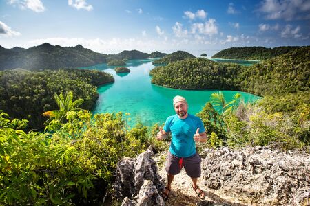 Tourists are on the top of the cliff of remote archipelago Pulau Wayag, Raja Ampat, Indonesiaの写真素材