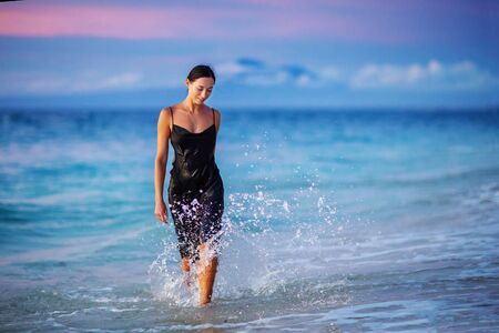 Beautiful woman by the ocean at sunset