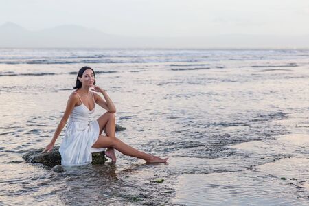 Beautiful woman by the ocean at sunsetの写真素材