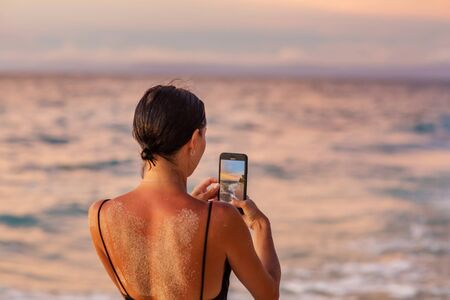 Beautiful woman by the ocean at sunsetの写真素材