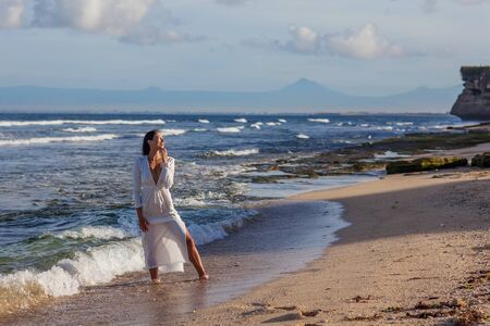 Beautiful woman by the ocean at sunsetの写真素材