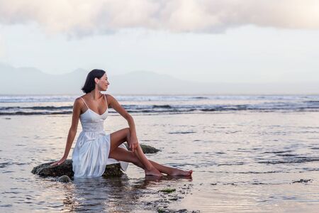 Beautiful woman by the ocean at sunsetの写真素材
