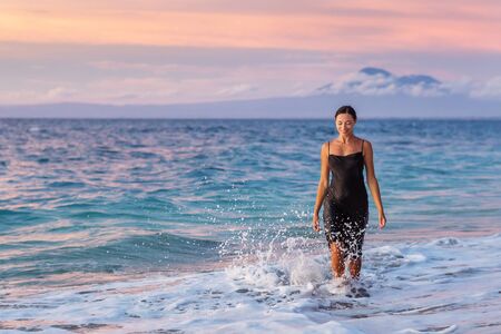 Beautiful woman by the ocean at sunsetの写真素材