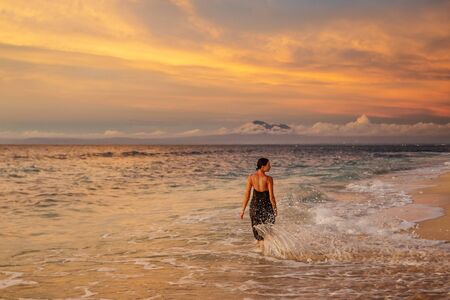 Beautiful woman by the ocean at sunsetの写真素材